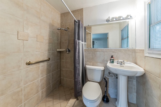 bathroom with tile walls, toilet, curtained shower, sink, and tile patterned flooring