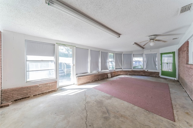 interior space featuring ceiling fan, brick wall, and a textured ceiling