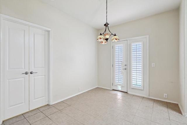 spare room featuring light tile patterned flooring and a notable chandelier