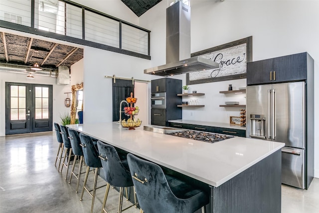 kitchen featuring open shelves, finished concrete flooring, a barn door, stainless steel appliances, and extractor fan