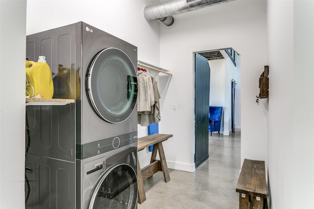 laundry room featuring laundry area, baseboards, and stacked washer / drying machine