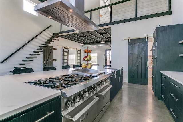 kitchen with high end stove, a sink, finished concrete floors, a barn door, and extractor fan