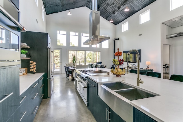 kitchen featuring a sink, open floor plan, finished concrete floors, island range hood, and range with two ovens