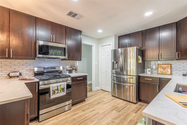 kitchen featuring light hardwood / wood-style floors, light stone countertops, stainless steel appliances, and backsplash