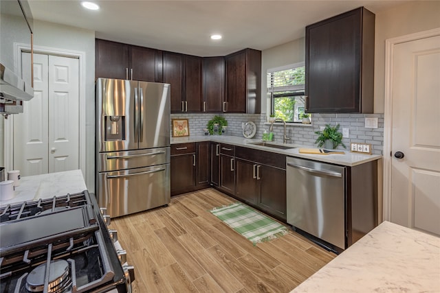 kitchen with decorative backsplash, sink, light hardwood / wood-style floors, appliances with stainless steel finishes, and range hood