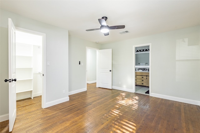 unfurnished bedroom featuring ceiling fan, hardwood / wood-style flooring, a spacious closet, and ensuite bath