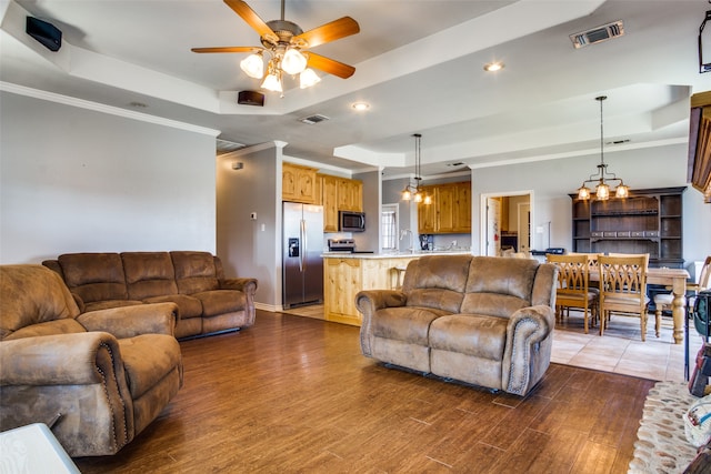 living room featuring sink, a tray ceiling, ceiling fan with notable chandelier, and hardwood / wood-style flooring