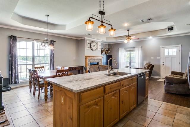 kitchen with a tray ceiling, sink, and a center island with sink