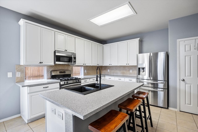 kitchen featuring appliances with stainless steel finishes, a kitchen island with sink, sink, and white cabinets