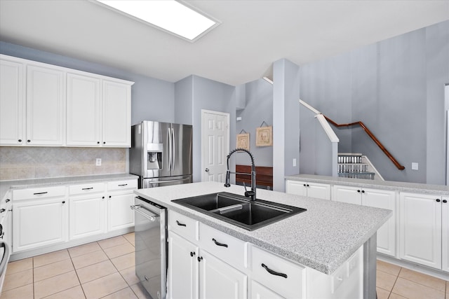 kitchen with an island with sink, appliances with stainless steel finishes, decorative backsplash, and white cabinetry