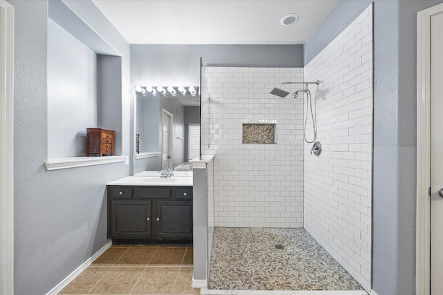 bathroom featuring a tile shower, tile patterned floors, and vanity