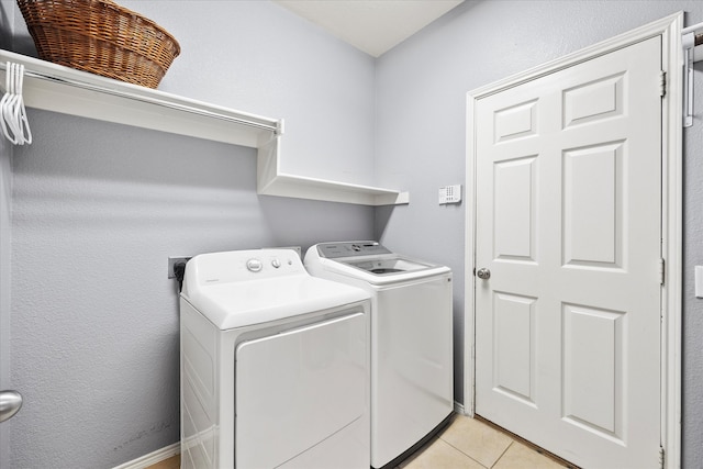 clothes washing area with light tile patterned floors and washer and dryer