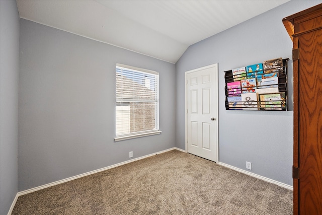 carpeted spare room featuring vaulted ceiling