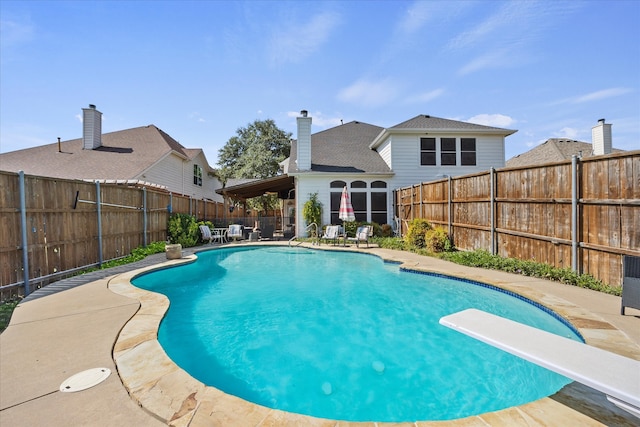 view of pool featuring a diving board and a patio