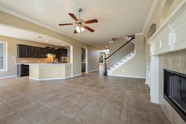 unfurnished living room with crown molding, light tile patterned floors, a fireplace, and ceiling fan