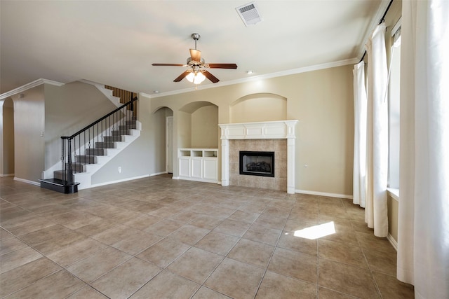 1310 Gold Coast Dr, Rockwall, TX 75087 - unfurnished living room featuring visible vents, light tile patterned flooring, a tile fireplace, ornamental molding, and a ceiling fan