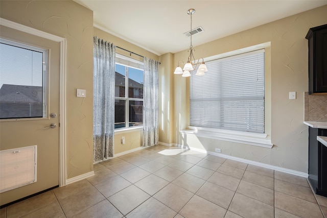 unfurnished dining area with a notable chandelier and light tile patterned floors