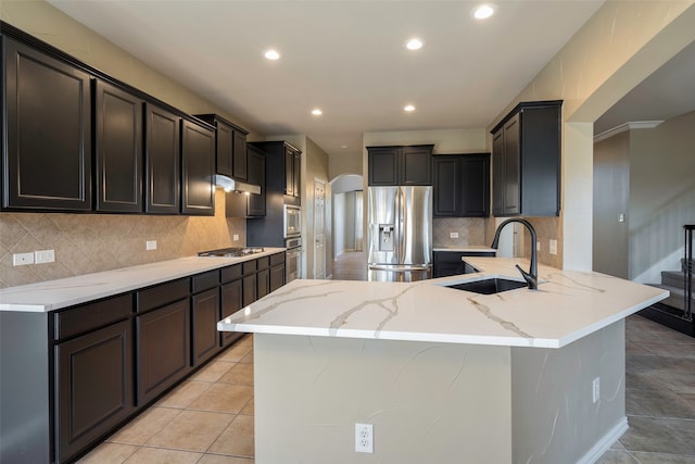 kitchen featuring tasteful backsplash, light stone countertops, sink, stainless steel appliances, and light tile patterned floors