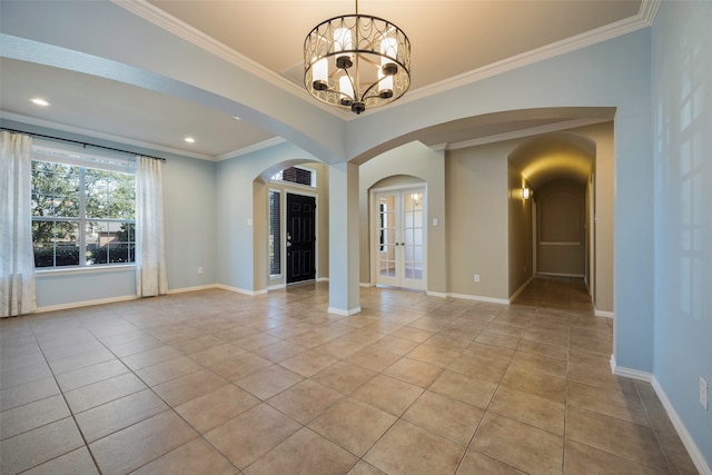 tiled spare room featuring ornamental molding and an inviting chandelier