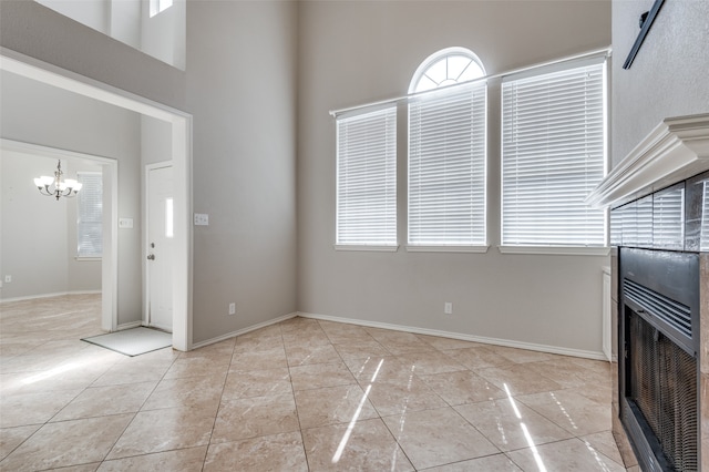 unfurnished living room with light tile patterned floors, a towering ceiling, and a notable chandelier