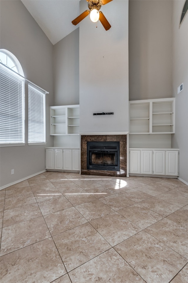 unfurnished living room featuring a healthy amount of sunlight, a premium fireplace, and high vaulted ceiling