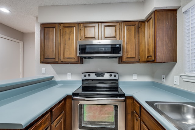 kitchen featuring a textured ceiling, sink, stainless steel appliances, and a wealth of natural light