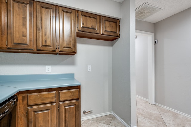 kitchen featuring light tile patterned floors, black dishwasher, and a textured ceiling