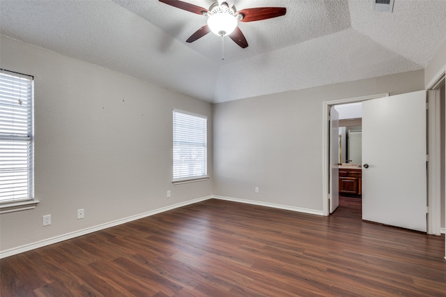 empty room featuring vaulted ceiling, dark hardwood / wood-style floors, and a raised ceiling