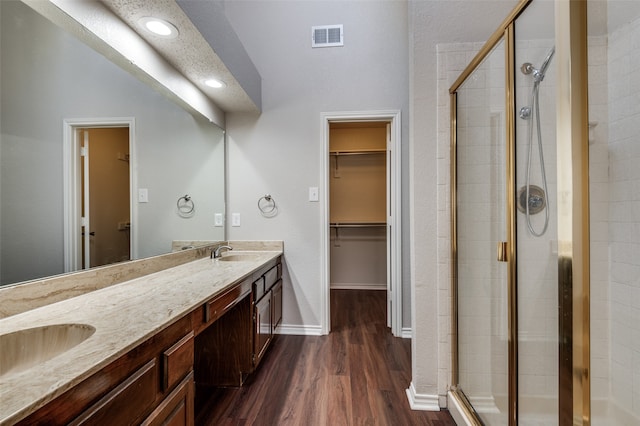 bathroom with hardwood / wood-style flooring, vanity, walk in shower, and a textured ceiling