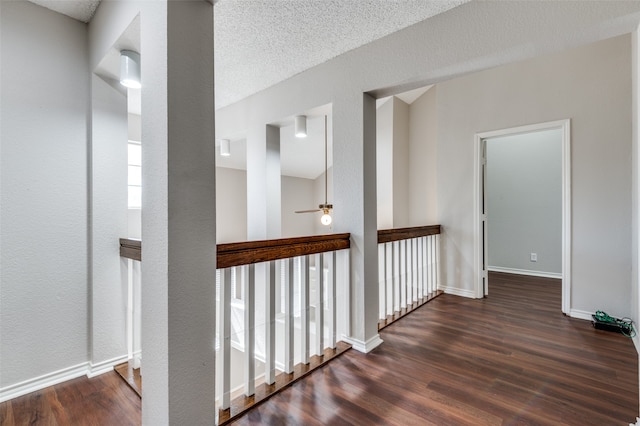 hallway with a textured ceiling, dark hardwood / wood-style floors, and a wealth of natural light