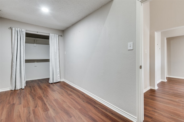 unfurnished bedroom with dark hardwood / wood-style flooring, a textured ceiling, and a closet