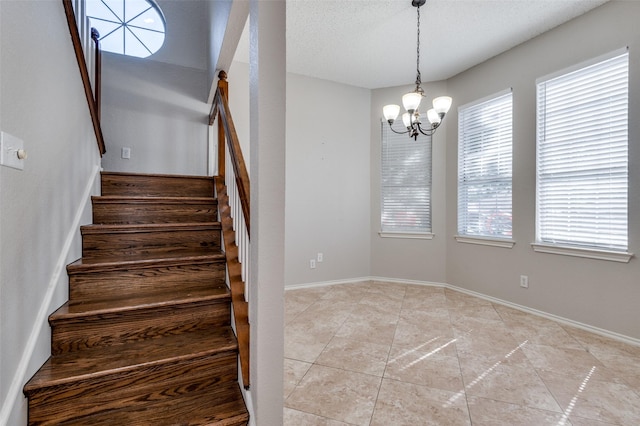 stairway featuring a chandelier, a textured ceiling, plenty of natural light, and tile patterned flooring