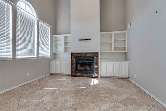 unfurnished living room with a tile fireplace, light tile patterned floors, and a high ceiling