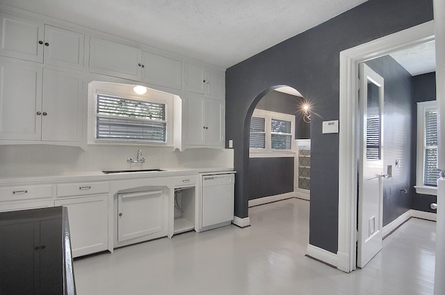 kitchen featuring white dishwasher, sink, a textured ceiling, and white cabinetry