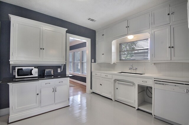 kitchen featuring light wood-type flooring, decorative backsplash, white appliances, sink, and white cabinetry