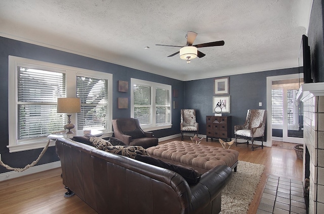 living room featuring light wood-type flooring, a healthy amount of sunlight, ceiling fan, and a textured ceiling