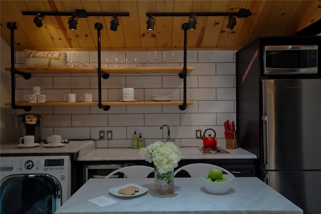 kitchen featuring backsplash, wooden ceiling, stainless steel appliances, and washer / clothes dryer