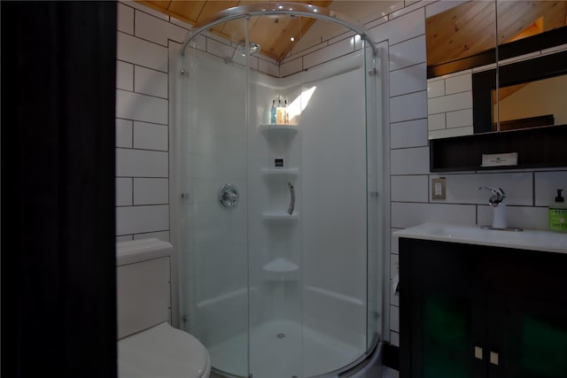 bathroom featuring vanity, lofted ceiling, a shower with shower door, tile walls, and toilet