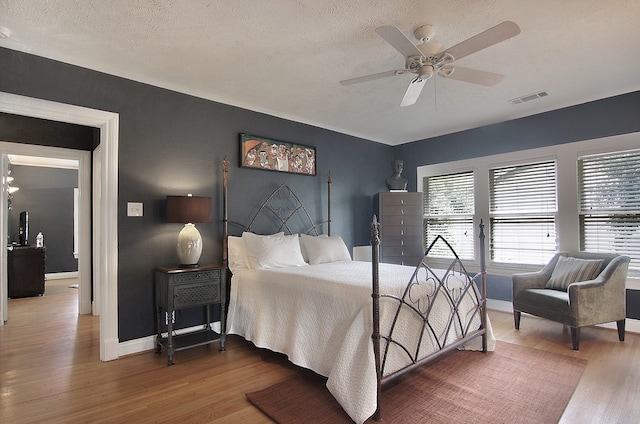 bedroom with hardwood / wood-style floors, a textured ceiling, and ceiling fan