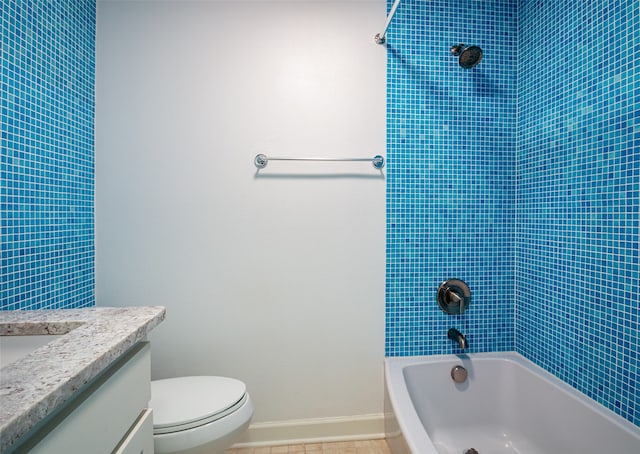 full bathroom featuring tile patterned flooring, tiled shower / bath, vanity, and toilet