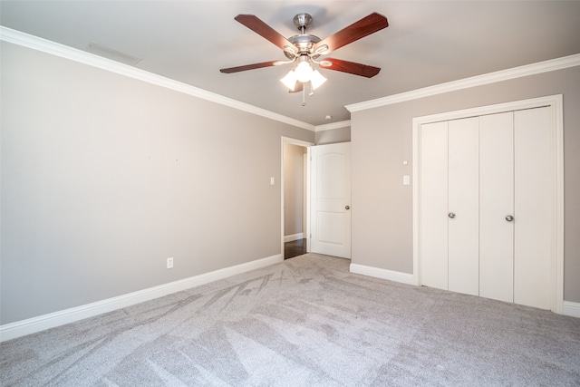 unfurnished bedroom featuring ceiling fan, carpet floors, a closet, and crown molding