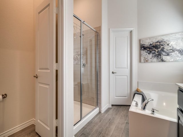full bathroom with a bath, baseboards, wood finished floors, and a shower stall