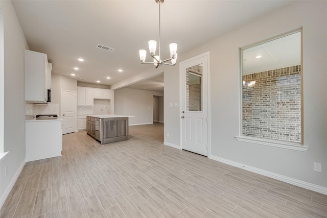 kitchen featuring white cabinetry, a notable chandelier, an island with sink, decorative light fixtures, and decorative backsplash