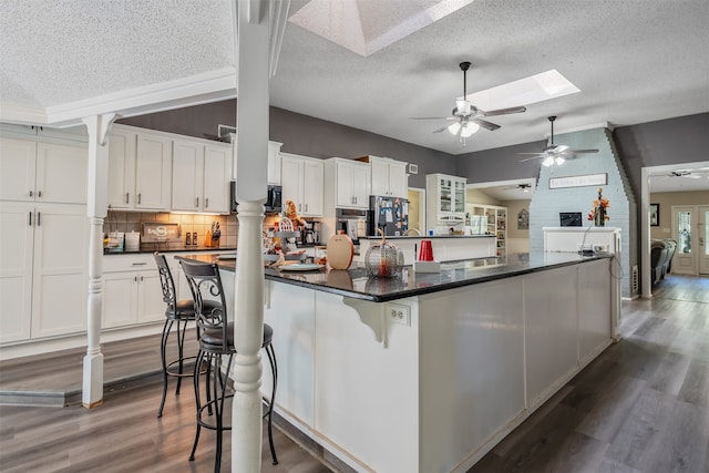 kitchen with a kitchen bar, a textured ceiling, and white cabinetry