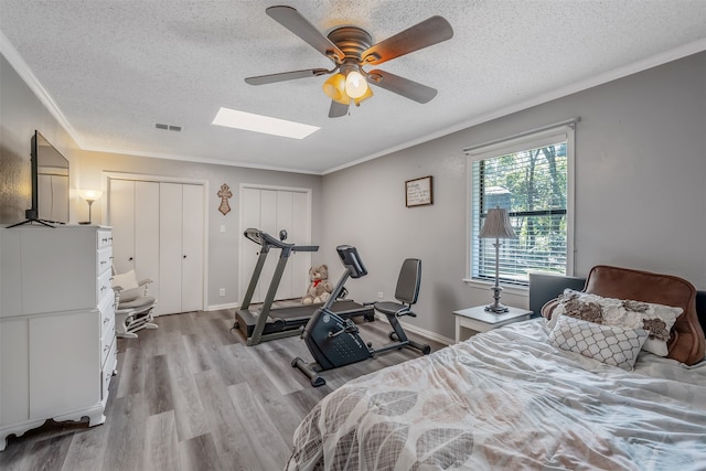 bedroom with crown molding, light hardwood / wood-style flooring, a textured ceiling, and ceiling fan