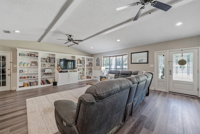 living room featuring dark wood-type flooring, vaulted ceiling with beams, and a textured ceiling