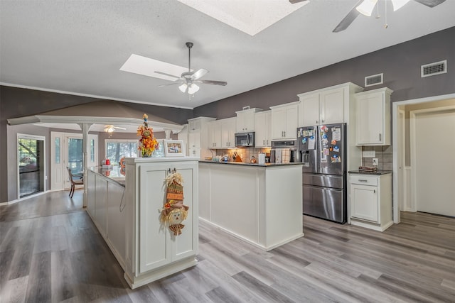 kitchen featuring white cabinets, appliances with stainless steel finishes, backsplash, and light hardwood / wood-style flooring