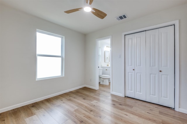 unfurnished bedroom featuring light wood-type flooring, a closet, ensuite bath, and ceiling fan