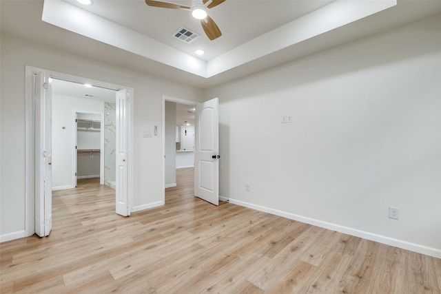 unfurnished bedroom with ceiling fan, light wood-type flooring, a walk in closet, and a closet