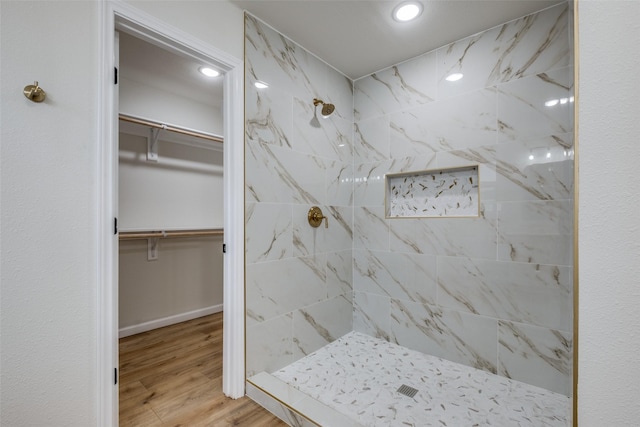 bathroom with a tile shower and hardwood / wood-style flooring